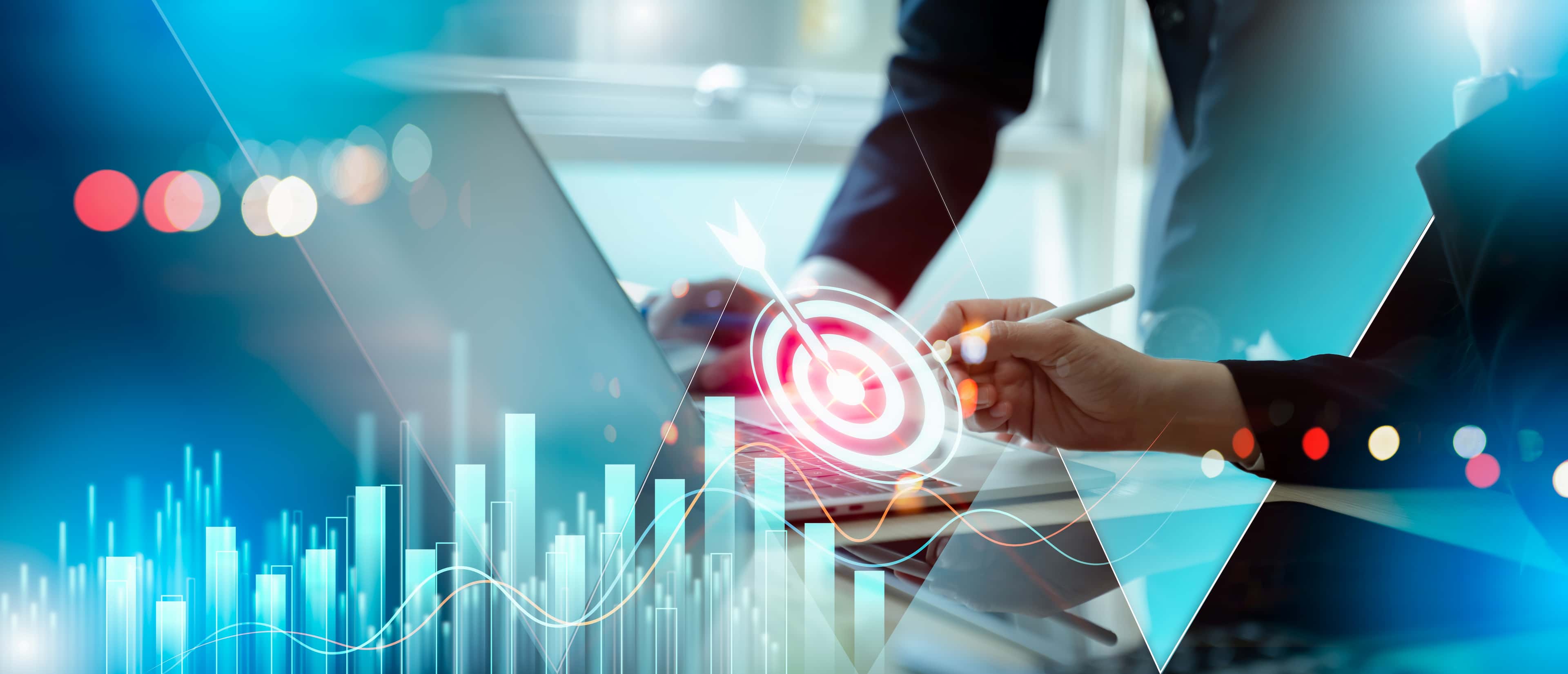 Businessperson working on laptop with digital overlay of target bullseye, bar charts, and growth graphs representing business goals.