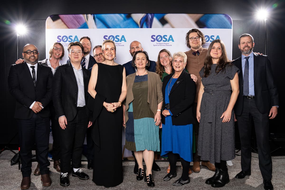 Group of professionals posing together at the SOSA Te Hāpai Hapori Spirit of Service Awards ceremony backdrop.
