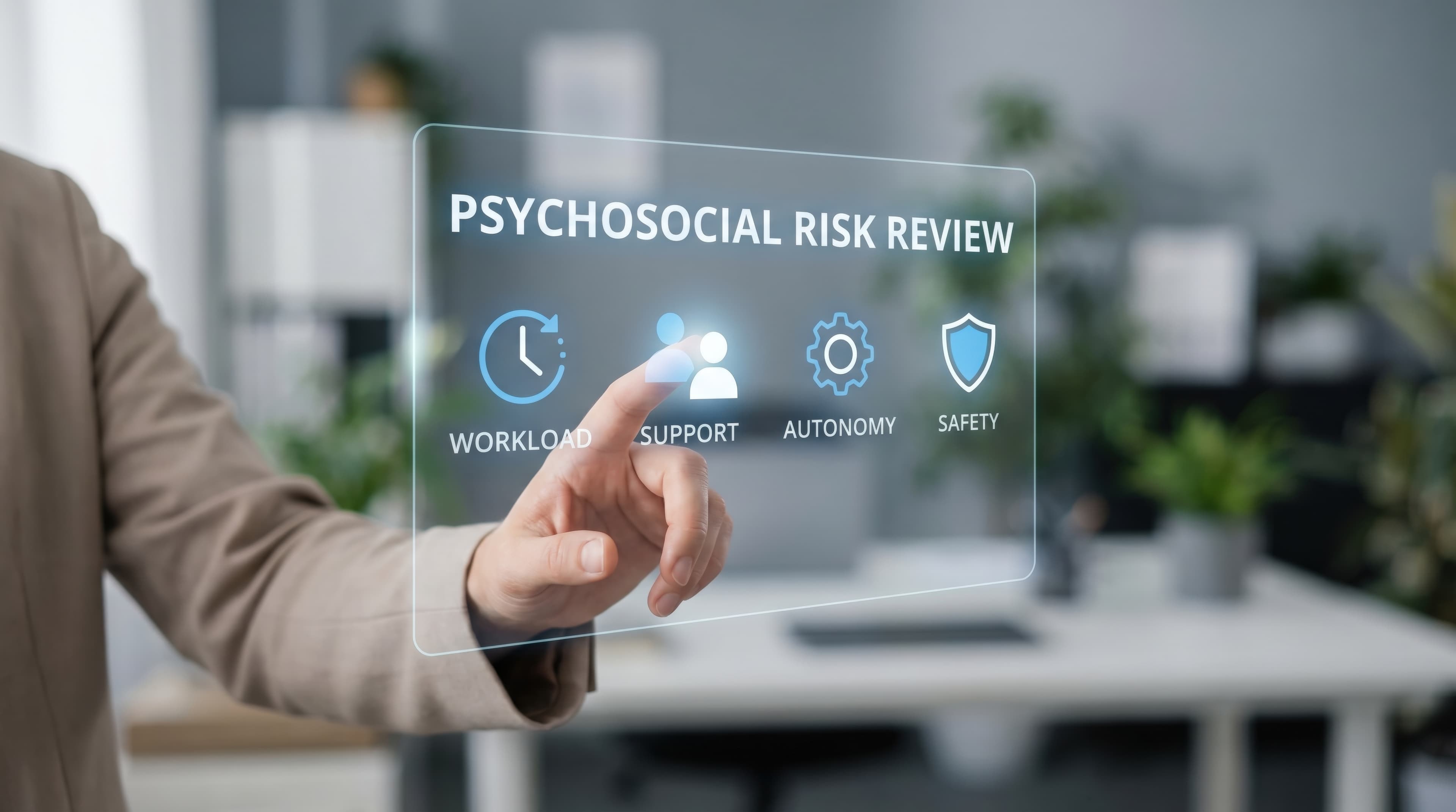 Person in a suit touching a virtual screen displaying "Psychosocial Risk Review" with icons for Workload, Support, Autonomy, and Safety.