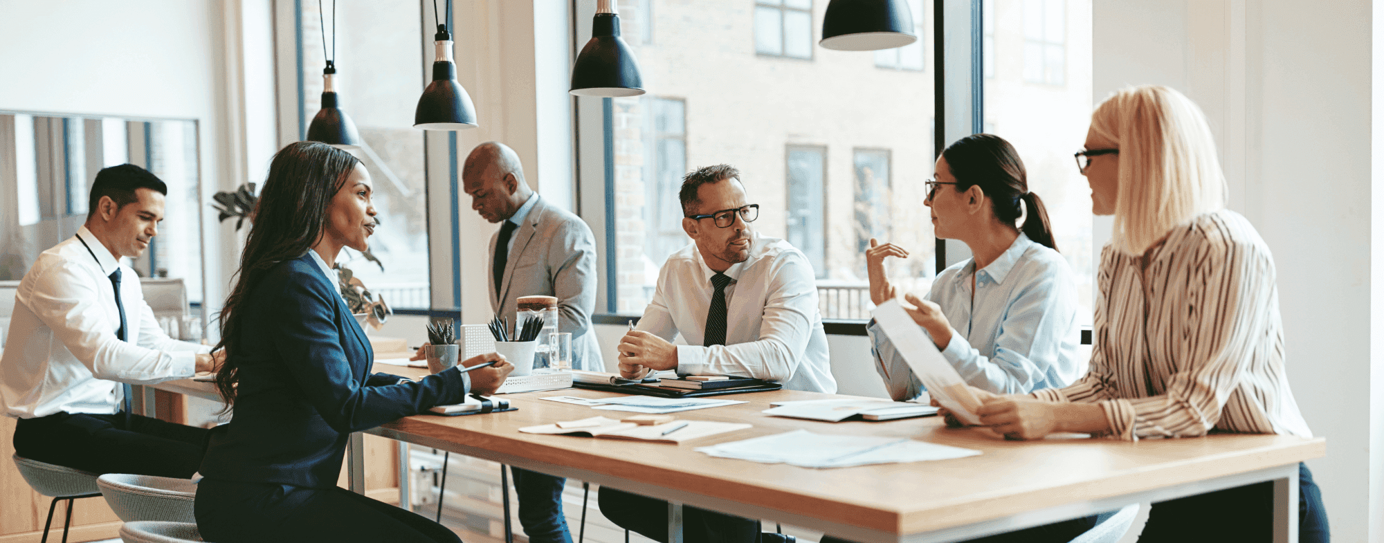 A diverse group of professionals engaged in a discussion around a conference table in a modern office setting.