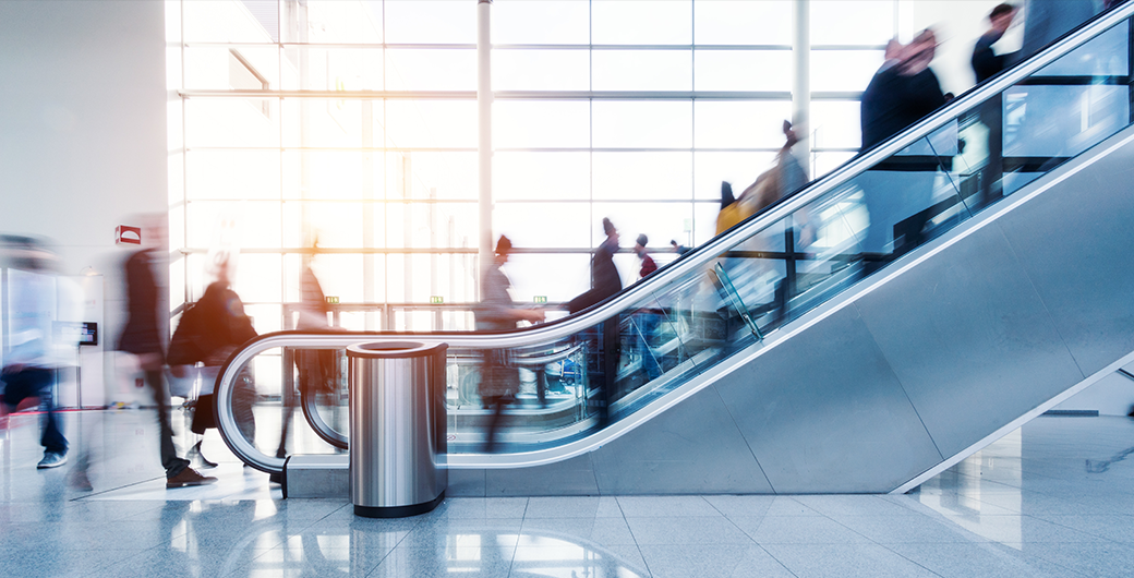 Image of blurred commuters going up an escalator