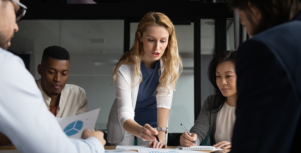 Image of young businesswoman explaining research results in graphs to colleagues