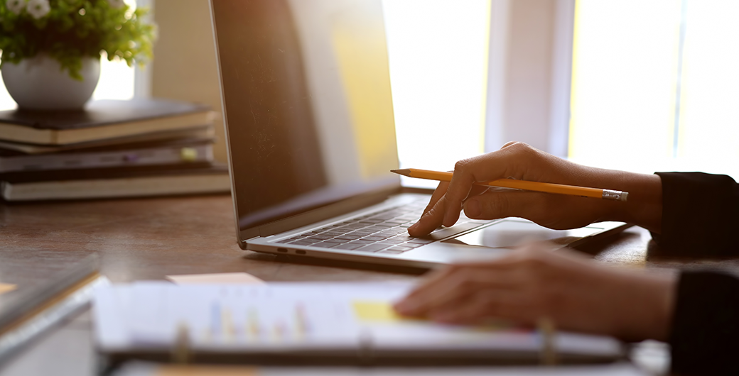 image of woman with laptop writing on a piece of paper