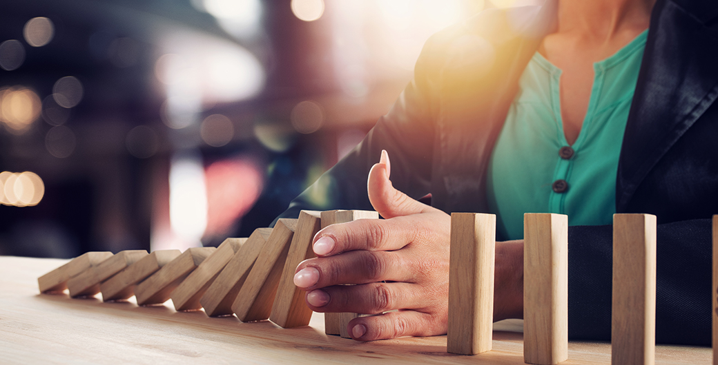 Businesswoman stops a chain fall like domino game. Concept of preventing crisis and failure in business.