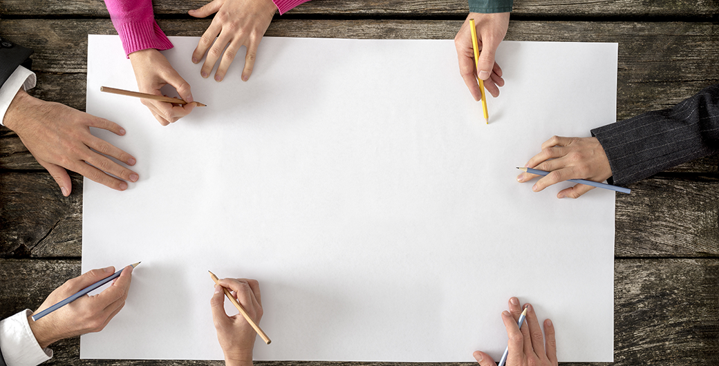 Six people working together over a large piece of paper