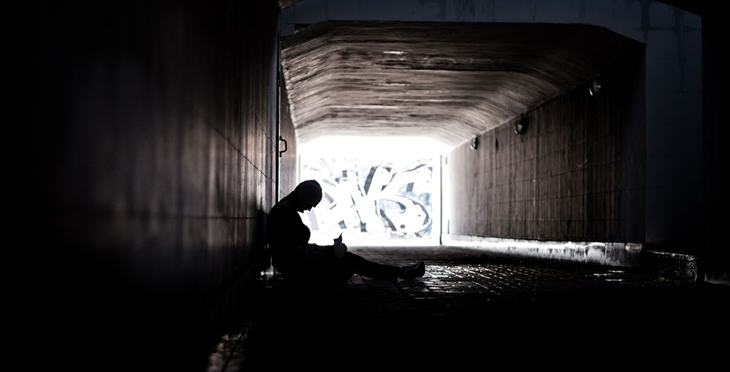 Young homeless man under a bridge